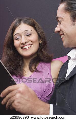 Stock Image - Couple holding a menu and smiling. Fotosearch