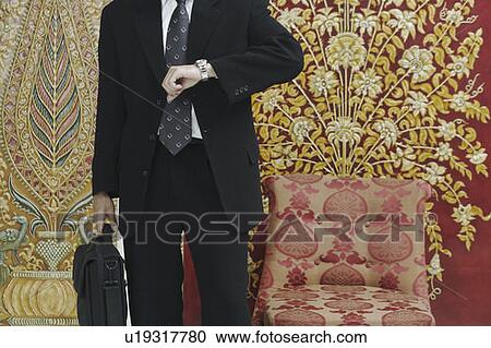 Mid section view of a businessman looking at his wristwatch View Large Photo Image Stock Image - Mid section view of a businessman looking at his wristwatch. Fotosearch
