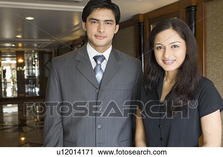 Stock Image - Portrait of a businessman and a businesswoman standing side by side in a hotel. Fotosearch