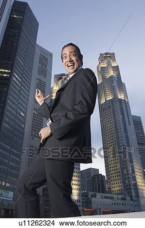 Portrait of a businessman dancing with skyscrapers in the background, Singapore View Large Photo Image Picture - Portrait of a businessman dancing with skyscrapers in the background, Singapore. Fotosearch