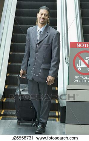 Stock Image - Portrait of a businessman pulling his bag and smiling. Fotosearch