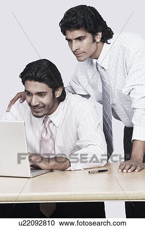 Two businessmen using a laptop View Large Photo Image Stock Image - Two businessmen using a laptop. Fotosearch