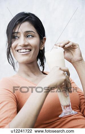 Close-up of a young woman holding a glass of milkshake and smiling View Large Photo Image Stock Image - Close-up of a young woman holding a glass of milkshake and smiling. Fotosearch