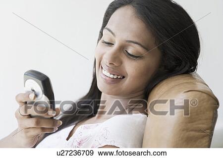 Close-up of a young woman text messaging and smiling View Large Photo Image Stock Photo - Close-up of a young woman text messaging and smiling. Fotosearch
