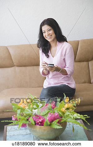 Young woman holding a mobile phone and smiling View Large Photo Image Stock Image - Young woman holding a mobile phone and smiling. Fotosearch