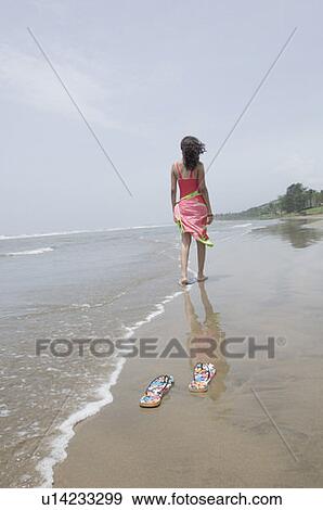 Rear view of a woman walking on the beach View Large Photo Image Stock Photo - Rear view of a woman walking on the beach. Fotosearch