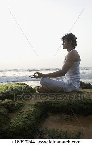 Side profile of a young man meditating on the beach View Large Photo Image Picture - Side profile of a young man meditating on the beach. Fotosearch