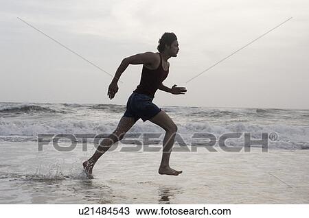 Side profile of a young man running on the beach View Large Photo Image Stock Image - Side profile of a young man running on the beach. Fotosearch