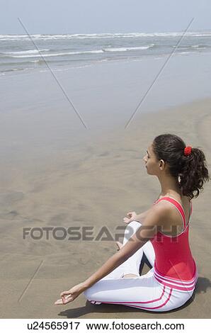 Stock Photo - Side profile of a young woman meditating on the beach. Fotosearch