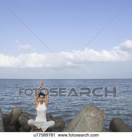 Young woman doing yoga on a rock View Large Photo Image Stock Image - Young woman doing yoga on a rock . Fotosearch