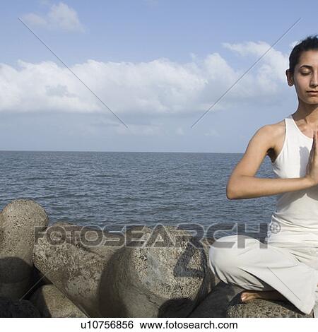 Stock Photograph - Young woman doing yoga on a rock . Fotosearch