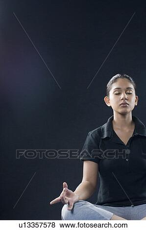 Young woman meditating in a lotus position View Large Photo Image Stock Photo - Young woman meditating in a lotus position. Fotosearch