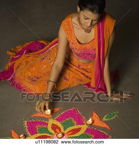 Stock Image - High angle view of a young woman making a rangoli. Fotosearch