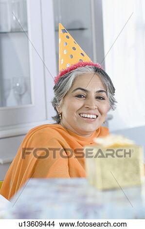 Portrait of a mature woman wearing a birthday hat and smiling View Large Photo Image Picture - Portrait of a mature woman wearing a birthday hat and smiling. Fotosearch