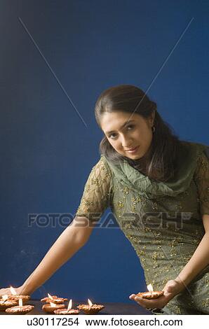 Picture - Portrait of a young woman lighting oil lamps. Fotosearch