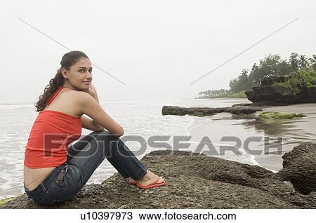 Portrait of a young woman sitting on a rock View Large Photo Image Stock Image - Portrait of a young woman sitting on a rock. Fotosearch
