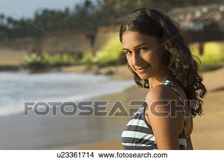 Picture - Portrait of a young woman standing on the beach and smirking. Fotosearch