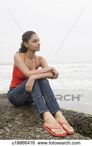 Young woman sitting on a rock and thinking View Large Photo Image Stock Photograph - Young woman sitting on a rock and thinking. Fotosearch