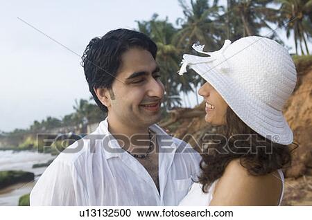 Close-up of a young couple looking at each other and smiling on the beach, Goa, India View Large Photo Image Stock Image - Close-up of a young couple looking at each other and smiling on the beach, Goa, India. Fotosearch