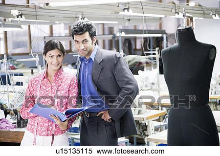 Stock Photography - Portrait of a businessman standing with a female fashion designer in a textile industry. Fotosearch