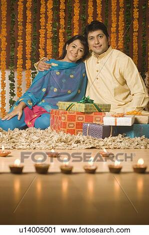 Stock Image - Portrait of a mid adult man and a young woman sitting beside gifts. Fotosearch