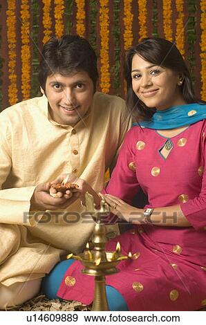Portrait of a mid adult man and a young woman holding a traditional diwali lamp and smiling View Large Photo Image Stock Photo - Portrait of a mid adult man and a young woman holding a traditional diwali lamp and smiling. Fotosearch