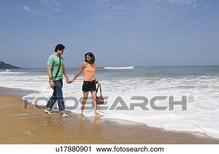 Side profile of a young couple holding hands and walking on the beach View Large Photo Image Stock Image - Side profile of a young couple holding hands and walking on the beach. Fotosearch