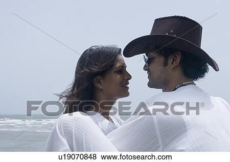 Side profile of a young couple looking at each other on the beach View Large Photo Image Stock Photo - Side profile of a young couple looking at each other on the beach. Fotosearch