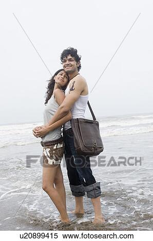 Side profile of a young man embracing a young woman from behind on the beach View Large Photo Image Stock Photography - Side profile of a young man embracing a young woman from behind on the beach. Fotosearch