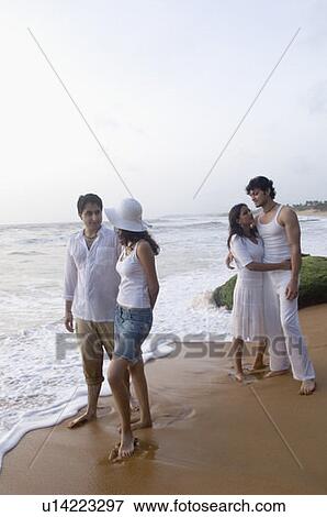Stock Photo - Two young couples standing on the beach. Fotosearch