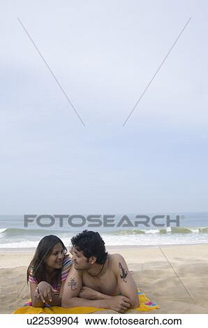 Young couple lying on the beach and smiling View Large Photo Image Picture - Young couple lying on the beach and smiling. Fotosearch