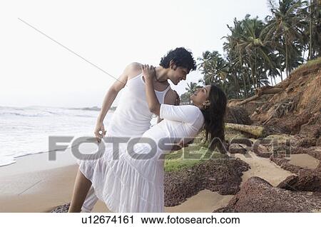 Stock Image - Young couple romancing on the beach, Goa, India. Fotosearch