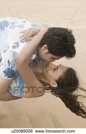 Stock Photo - Young couple romancing on the beach. Fotosearch