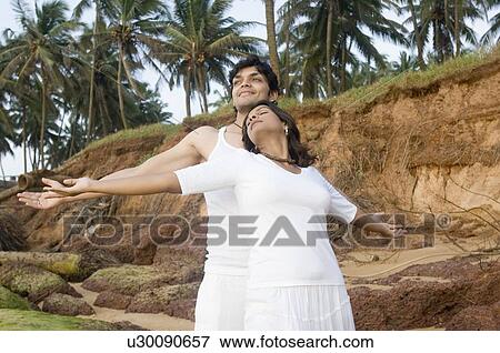 Stock Photo - Young couple smiling with their arms outstretched. Fotosearch