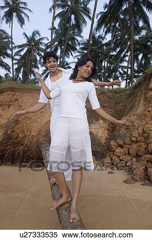 Young couple walking on a tree trunk View Large Photo Image Stock Photography - Young couple walking on a tree trunk. Fotosearch