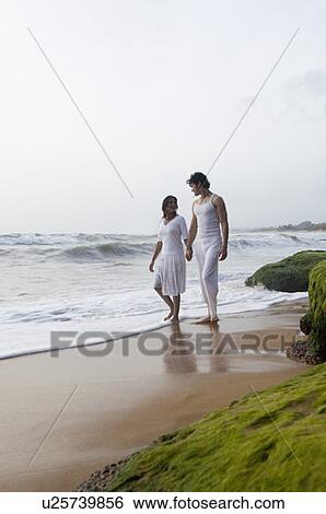 Young couple walking on the beach with holding hands View Large Photo Image Stock Photograph - Young couple walking on the beach with holding hands. Fotosearch
