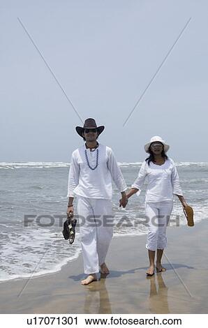 Young couple walking with holding hands on the beach View Large Photo Image Stock Image - Young couple walking with holding hands on the beach. Fotosearch