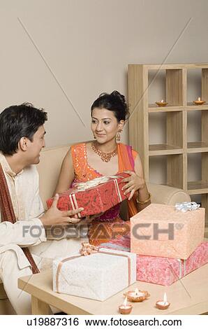 Stock Photograph - Young man giving a gift to a young woman. Fotosearch