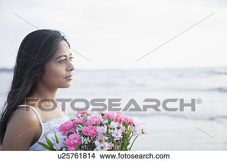 Close-up of a young woman holding a bouquet of flowers on the beach View Large Photo Image Picture - Close-up of a young woman holding a bouquet of flowers on the beach. Fotosearch