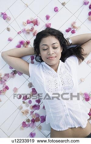 Stock Photo - High angle view of a young woman lying on the floor with her hands behind her head. Fotosearch