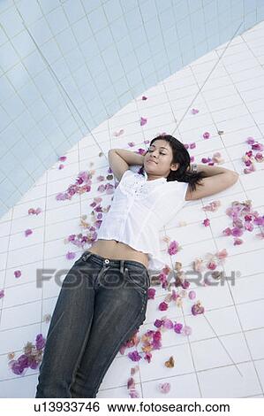 High angle view of a young woman lying on the floor with her hands behind her head View Large Photo Image Stock Photograph - High angle view of a young woman lying on the floor with her hands behind her head. Fotosearch