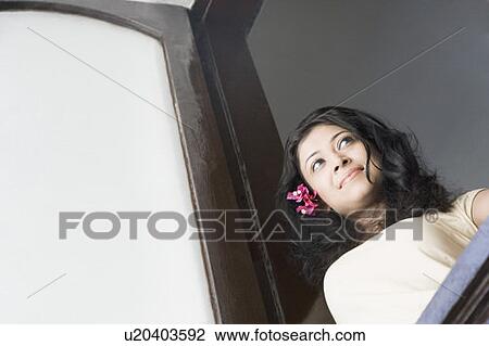 Low angle view of a young woman looking through a window View Large Photo Image Stock Image - Low angle view of a young woman looking through a window. Fotosearch
