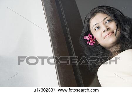 Stock Photo - Low angle view of a young woman looking through a window. Fotosearch