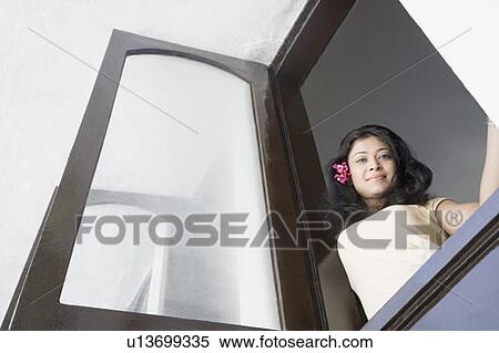 Stock Photography - Low angle view of a young woman looking through a window. Fotosearch