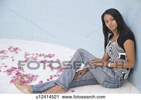 Stock Image - Portrait of a young woman sitting in an empty swimming pool. Fotosearch