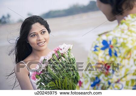 Rear view of a young man giving a bouquet of flowers to a young woman View Large Photo Image Stock Photography - Rear view of a young man giving a bouquet of flowers to a young woman. Fotosearch
