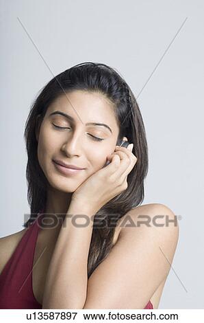 Stock Photo - Close-up of a young woman talking on a mobile phone with her eyes closed. Fotosearch