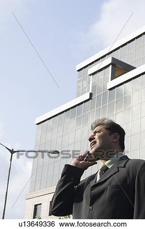 Low angle view of a businessman talking on a mobile phone View Large Photo Image Stock Photograph - Low angle view of a businessman talking on a mobile phone. Fotosearch
