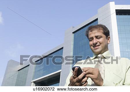 Low angle view of a businessman using a mobile phone with a stylus View Large Photo Image Stock Image - Low angle view of a businessman using a mobile phone with a stylus. Fotosearch