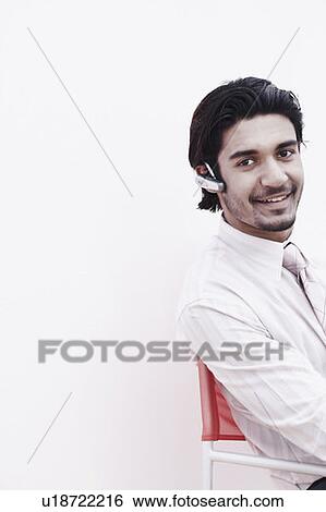 Stock Photograph - Portrait of a businessman wearing a hands free device. Fotosearch